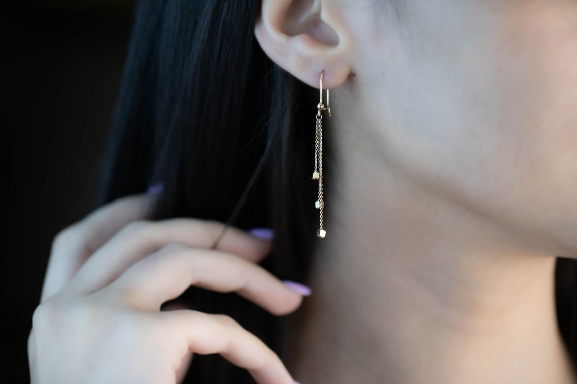 woman with oval face wearing gold dangle earrings